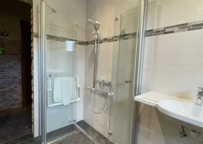 Gommern: Auch in kleinsten Bädern kann man durch den Einsatz von Glas-Pendel-Falttüren über Eck den gewünschten und geforderten Platzbedarf nach DIN 18040 erreichen. Für eine größtmögliche Sicherheit beim Duschen sorgen der Duschklappsitz und die Brausehaltestange.